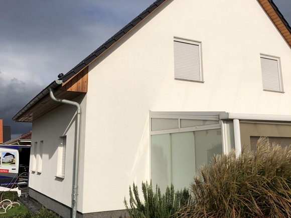 Frisch gereinigte, helle Fassade eines Wohnhauses vor dunklem Himmel.