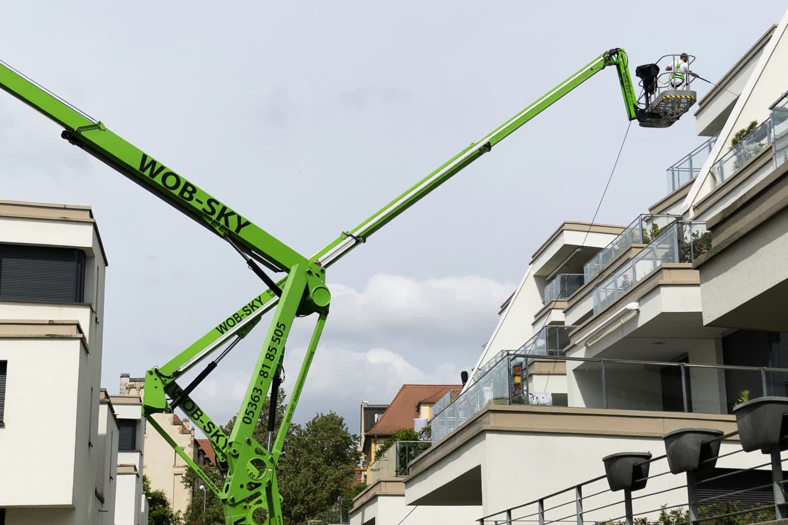 Die gemietete Arbeitsbühne steht im Hof, der Ausleger reicht über die oberen Balkone bis an die Fassade.