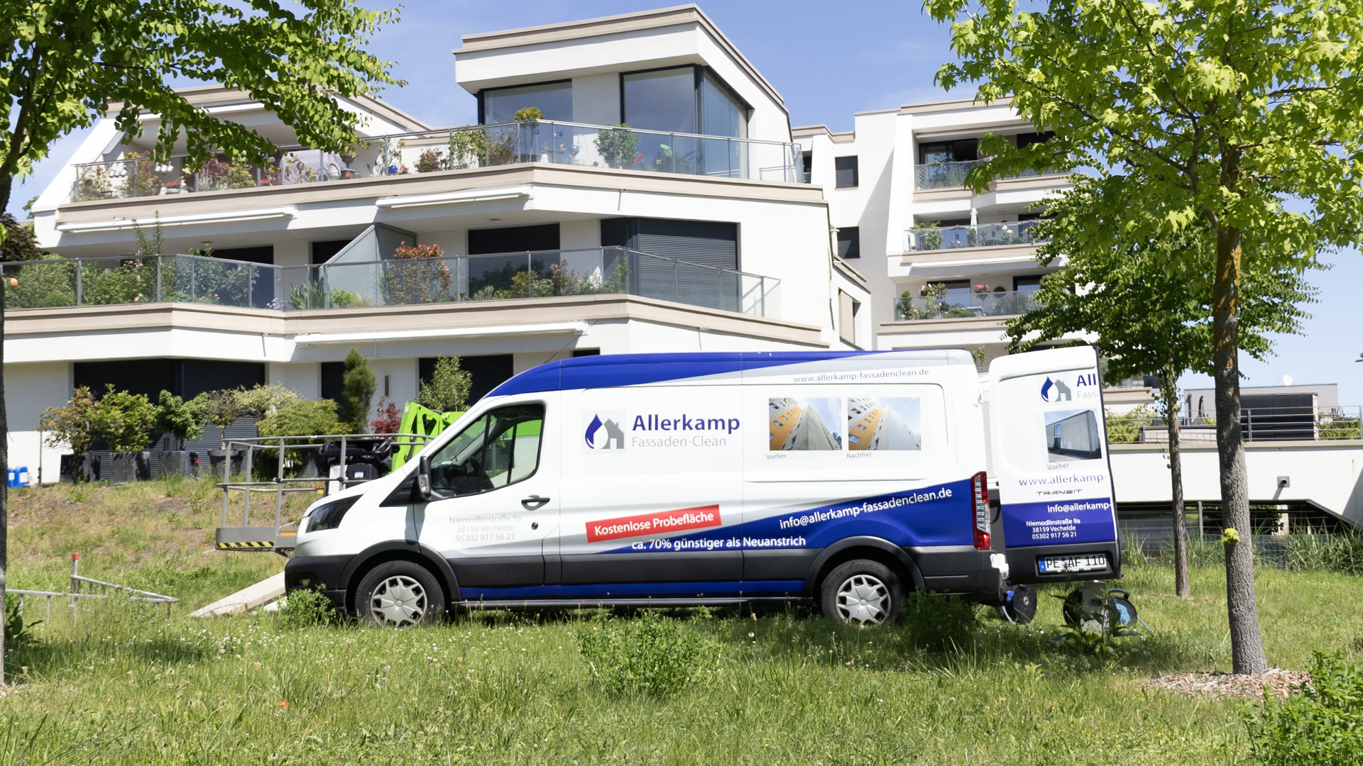 Der beschriftete Firmentransporter von Allerkamp Fassaden-Clean vor einer frisch gereinigten Wohnanlage.