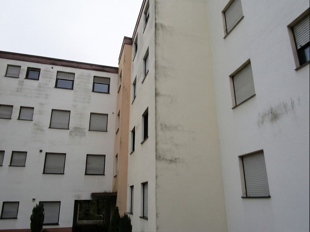 Wohnblock mit verschmutzter Giebelwand, vor der Reinigung.